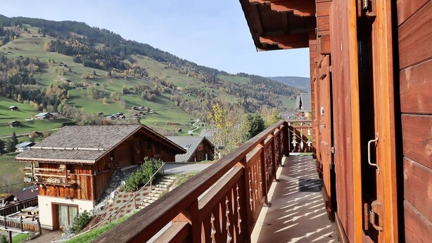A wooden balcony with a view of a valley and houses. - Family Chalet: Sleeps 10, Near Village & Slopes, WiFi, Fireplace, BBQ, Game Room (Arêches-Beaufort)