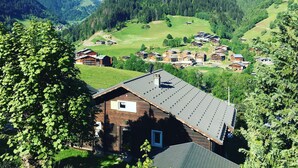 A mountain village with traditional wooden houses, a clear sky, and snow-capped mountains in the background. - Contemporary chalet for 8, 4 bedrooms, mountain views, parking, near village (Arêches-Beaufort)