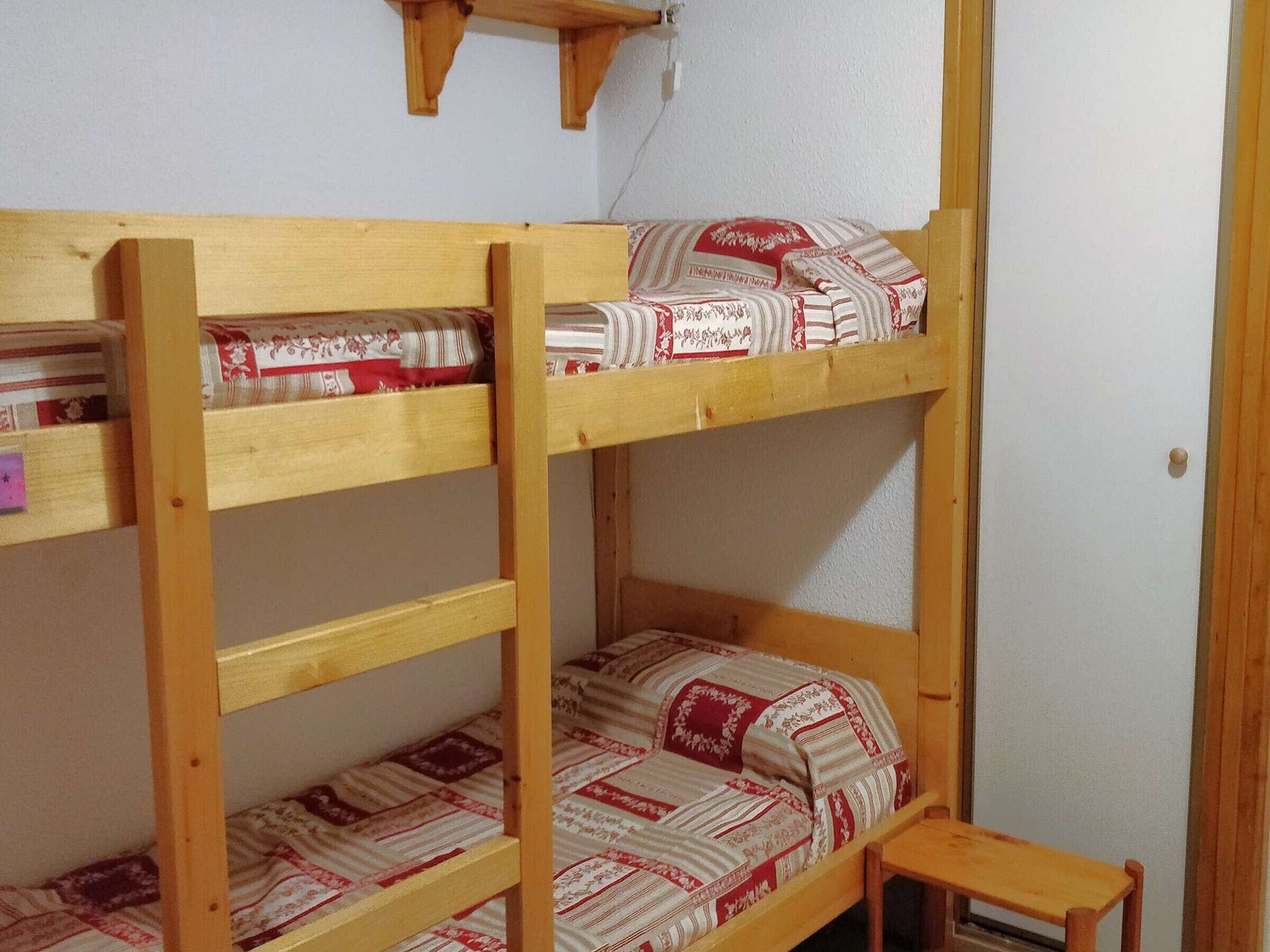 Una cama litera con estructura de madera y ropa de cama estampada.