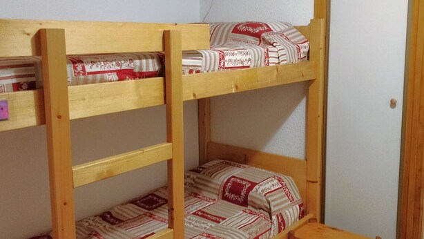 Een stapelbed met een houten frame en beddengoed met een patroon.
