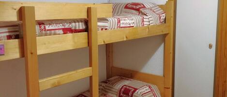 Una cama litera con estructura de madera y ropa de cama estampada.