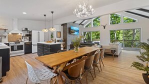 A spacious kitchen with a central island, modern appliances, and large windows offering views of the outdoors.