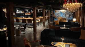 A bar area with a counter, bar stools, and a mural with the letters "LBD". - Speakeasy & Pool · 2BR Sleeps 6 · Dog-Friendly (Nashville)