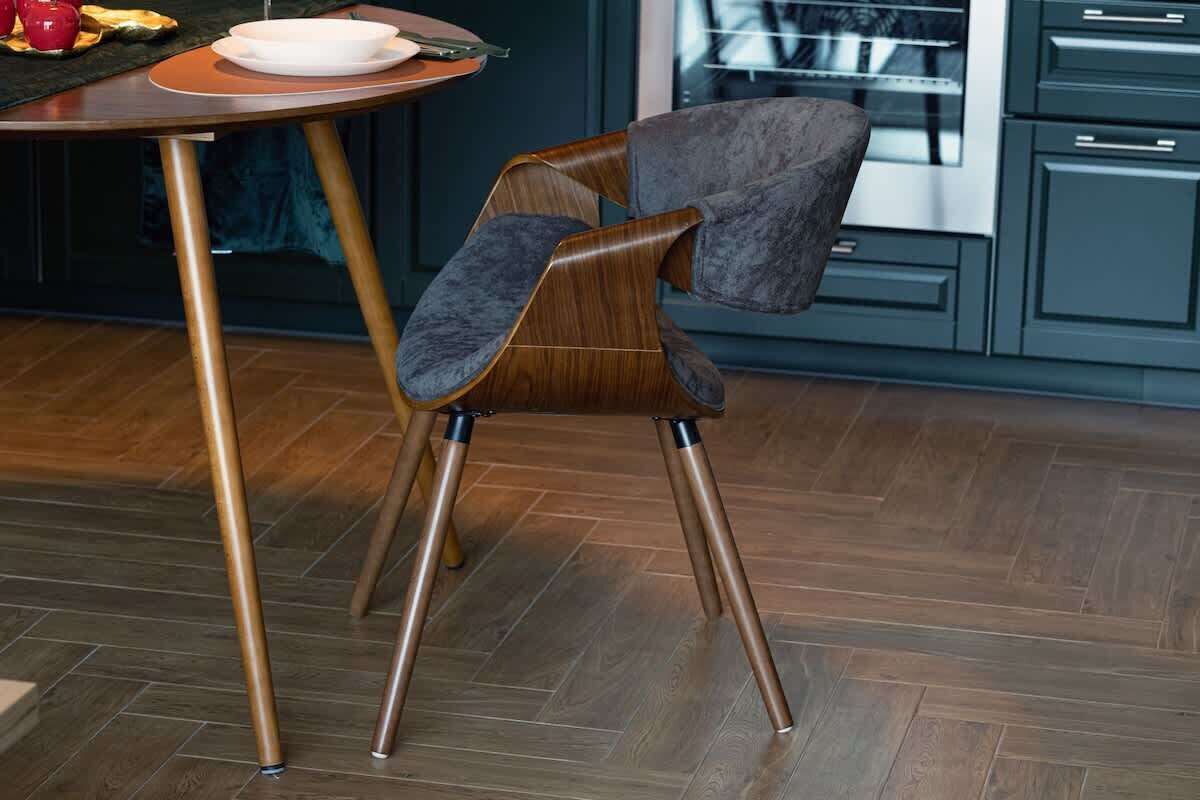 A modern kitchen with a wooden dining table and a dark upholstered chair with metal legs.