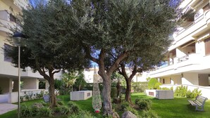 A courtyard with a large tree, a lamp post, and a bench. - COSTA DE LA LUZ APARTMENT (Rota)