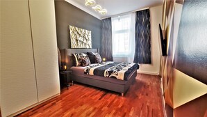 A modern bedroom with a bed, bedside table, and a large window with curtains. - Vienna CityApartments - Luxury 2 (Vienna)
