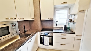 A modern kitchen with white cabinets, a built-in microwave, a sink, and a window with a view. - Vienna CityApartments - Luxury 2 (Vienna)