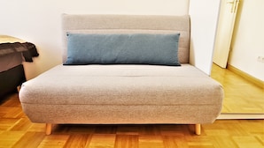 A small, single-bed room with a light-colored sofa and a blue pillow. - Vienna CityApartments - Luxury 2 (Vienna)