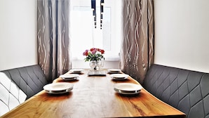 A dining table with six plates and two glasses, flanked by dark upholstered chairs, with a vase of flowers in the center. - Vienna CityApartments - Luxury 2 (Vienna)