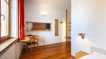 Una habitación pequeña con un escritorio de madera, una silla y una cama.