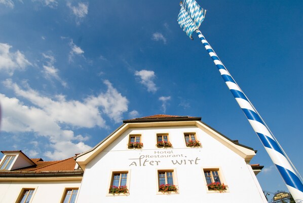 A hotel with a sign reading "Hotel Restaurant. Alter Wirt" and a tall blue and white striped pole in the background. - Alter Wirt GmbH in Grünwald (Gruenwald)