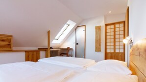 A bedroom with two beds, a skylight, a wooden desk, and a traditional Japanese sliding door.