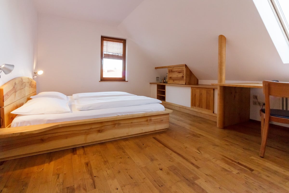 A bedroom with a wooden bed, a desk, and a window.