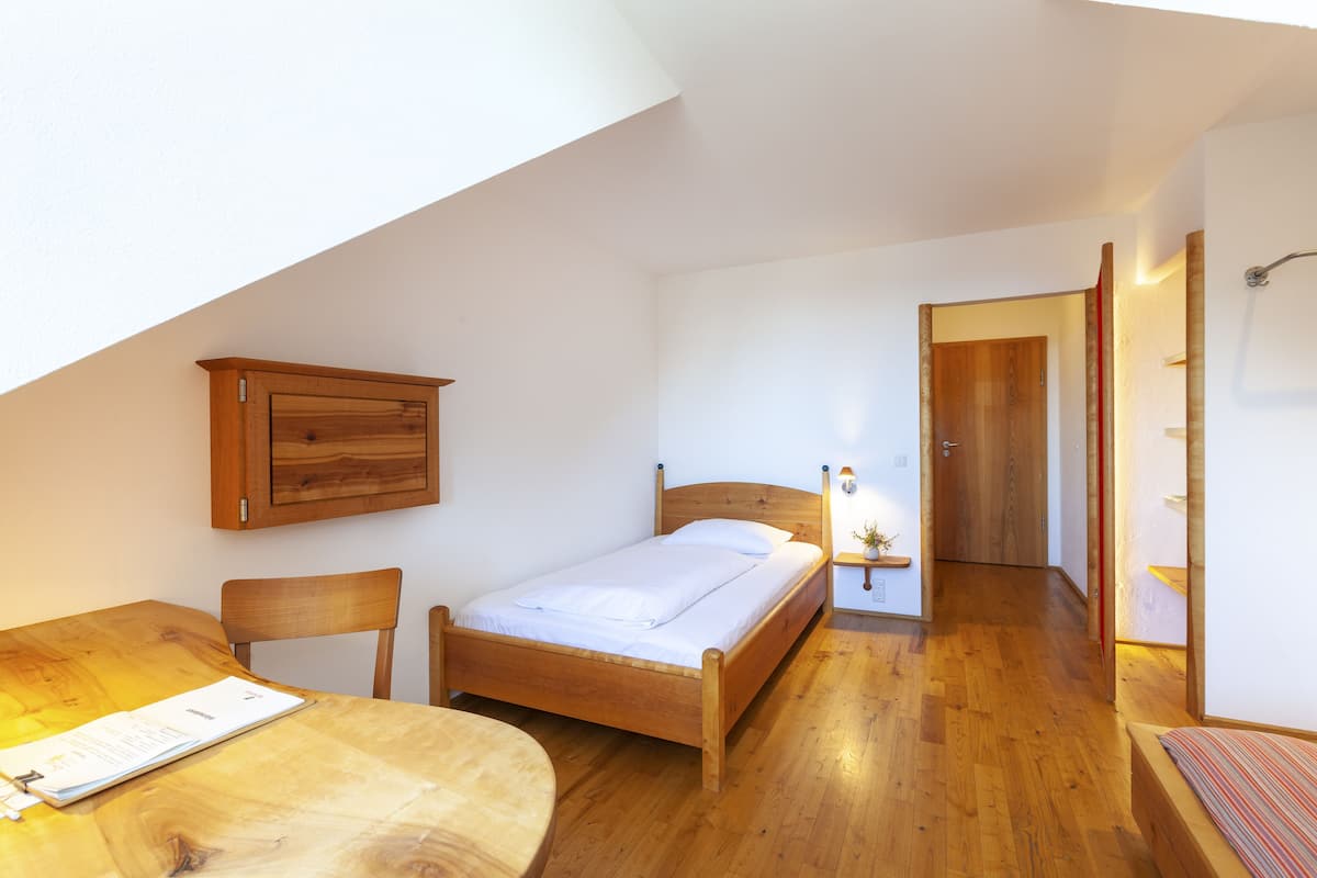 A bedroom with a wooden bed, a wooden desk, and a chair.