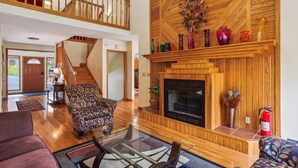 A spacious living room with a fireplace, a staircase, and a view of the outdoors.
