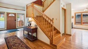 A wooden staircase with a handrail, a dark wooden console table with a lamp, and a patterned rug on a wooden floor.