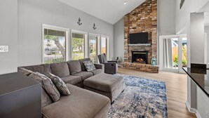 Una sala de estar moderna con un sofá modular, una chimenea y un televisor grande.