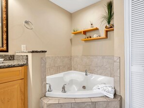 Un baño con una bañera independiente, armarios de madera y paredes color beige.