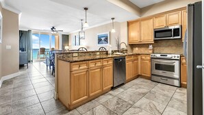 Una cocina moderna con encimeras de granito, armarios de madera y electrodomésticos de acero inoxidable, e una isla grande.