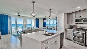 Una cocina moderna con una isla central, electrodomésticos de acero inoxidable y vistas al océano.