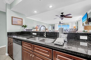 A modern kitchen with a granite countertop, stainless steel sink, and wooden cabinets.