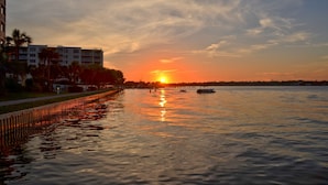 Blick auf das Wasser mit Gebäuden und einem Sonnenuntergang.