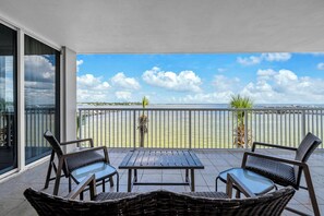 A balcony with a view of the sea, furnished with wicker chairs and a table. - Heron 303-HUGE CORNER CONDO w/ Wrap Around Balcony overlooking Lazy River & Bay! (Fort Walton Beach)