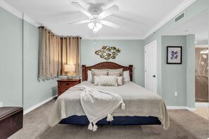 Une chambre à coucher comprenant un lit, une table de chevet, une lampe, un ventilateur de plafond et un élément de décoration murale.