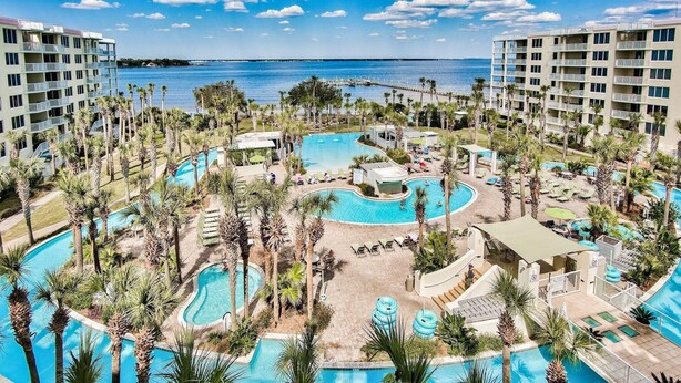 Et resort med flere swimmingpools, palmer og havudsigt.