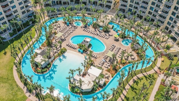 An aerial view of a resort with multiple swimming pools, palm trees, and sun loungers.