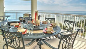 A round table set for dining with chairs, a view of the sea, and a railing. - Heron 604-Watch for Dolphins from your balcony!  3 BR Condo with Great Views (Fort Walton Beach)