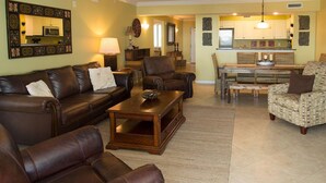 A living room with a brown leather sofa, a wooden coffee table, and a patterned armchair. - Heron 604-Watch for Dolphins from your balcony!  3 BR Condo with Great Views (Fort Walton Beach)