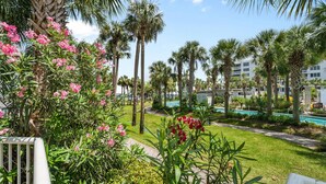 A resort with a pool, palm trees, and a well-maintained garden.