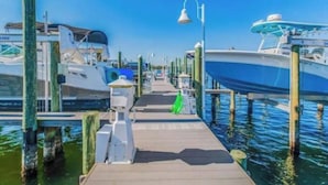 A marina with boats docked at wooden piers, a walkway, and a street lamp.