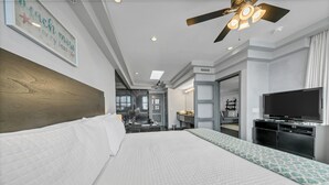 A hotel room with a large bed, a ceiling fan, a TV, and a bathroom visible through an open door.