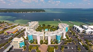 A coastal hotel with multiple buildings, a central pool, and a marina in the background.