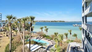 Een resort met een zwembad, palmbomen en uitzicht op zee.