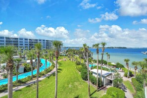 Een resort met een zwembad, palmbomen en uitzicht op de oceaan.