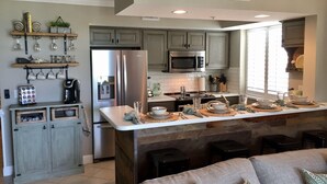 Una cocina moderna con una isla central, electrodomésticos integrados y una zona de comedor con sofá.