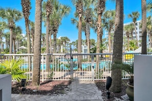 A pool area with palm trees, a clear sky, and a gated entrance.