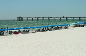 Guests can enjoy a serene beach experience with access to the ocean and shaded areas under the umbrellas.