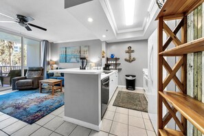 Relax in a spacious living area with a central island, sofa, and chair, offering a view of palm trees outside.