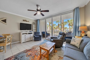 Relax in this stylish living room with a large flat-screen TV, comfortable sofas, and a ceiling fan.