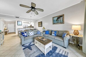 Un salon moderne avec un canapé gris, une table basse et un ventilateur de plafond.
