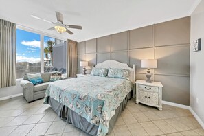Une chambre à coucher avec un lit, une table de chevet, une lampe, un canapé et une vue sur l’extérieur.