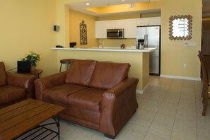 A living room with a brown leather sofa, a wooden coffee table, and a small side table with a plant. - Pelican PH04---1 BR + Bunk Penthouse @ Destin West (Fort Walton Beach)