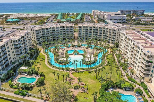A resort with multiple buildings, a central pool area, and a view of the ocean.