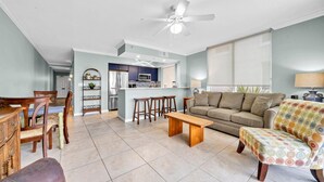 A spacious living room with a sofa, a coffee table, and a dining area with chairs and a table. - SANDPIPER 308-BAYSIDE CONDO @ DESTIN WEST SLEEPS 7 (Fort Walton Beach)