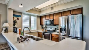 A modern kitchen with a large island, stainless steel appliances, and wooden cabinets.