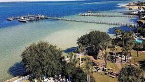 A coastal area with a pier extending into the water, surrounded by trees and a clear sky.